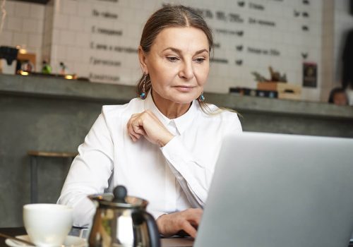 older woman working on a laptop at a cafe